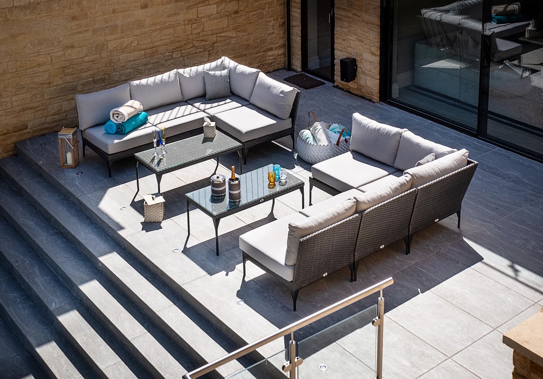 Outdoor pool-lounge area featuring glassware towelling and champagne flutes within the exterior of a luxury home