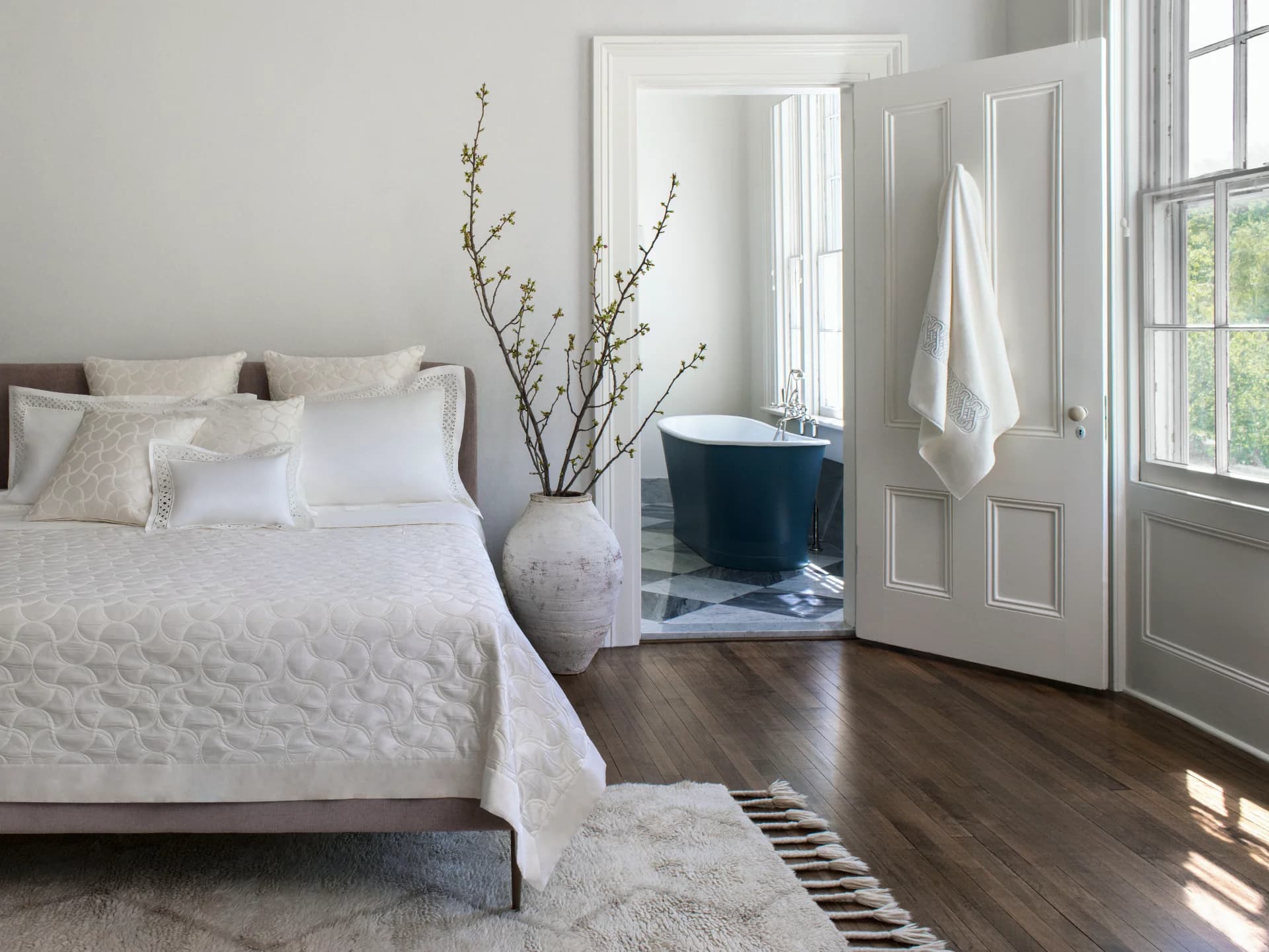 A beautifully made bed with luxurious white and gold linens.